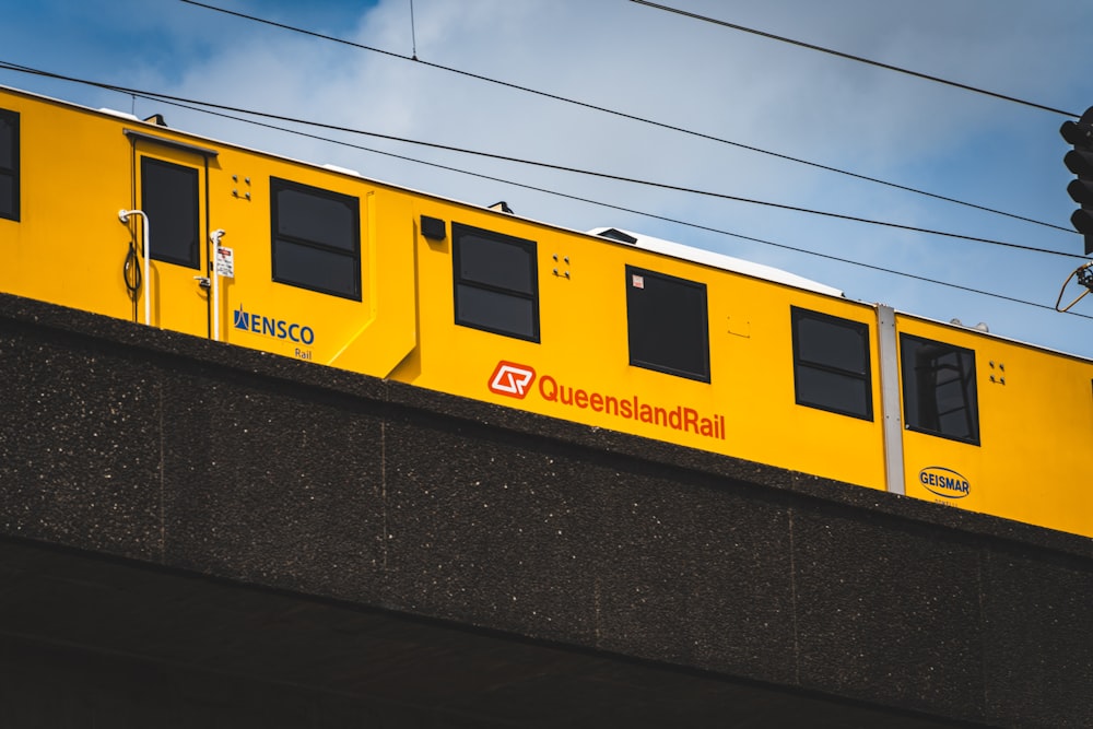 a yellow train traveling over a bridge under power lines