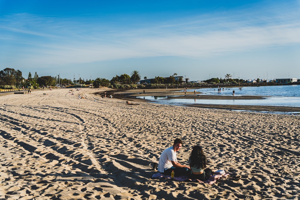 Dos personas sentadas en una playa junto al océano