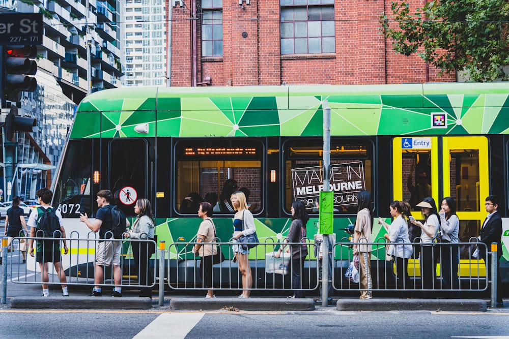 a green and yellow bus stopped at a bus stop