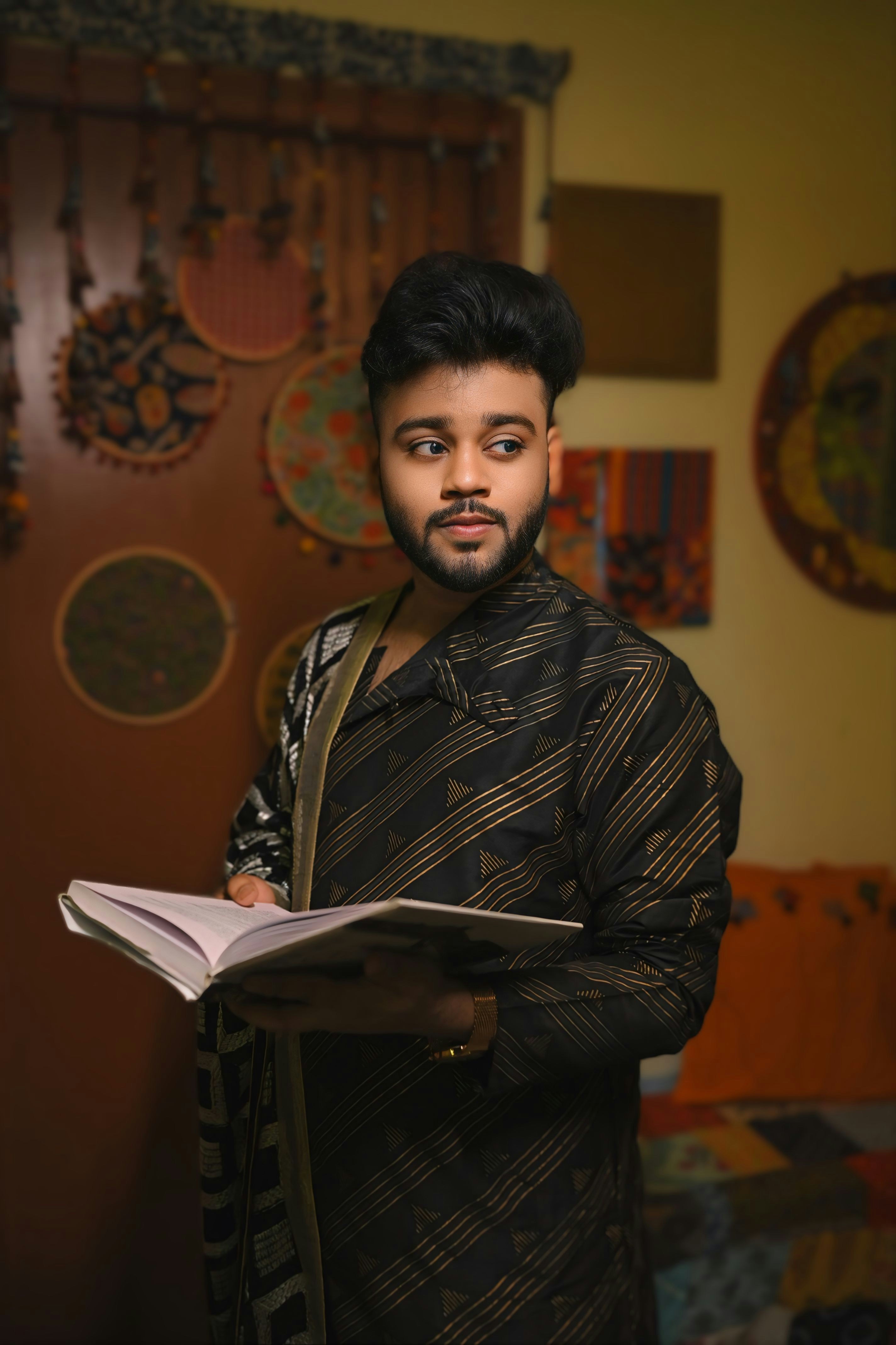 a man standing in a room holding a book