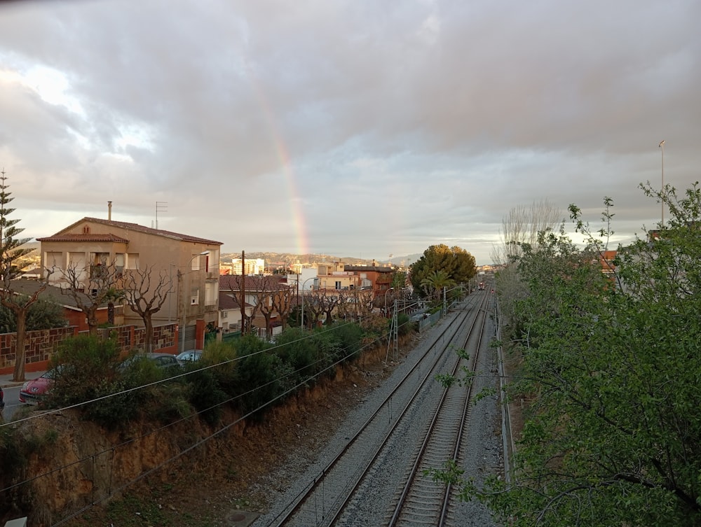 a rainbow in the sky over a train track