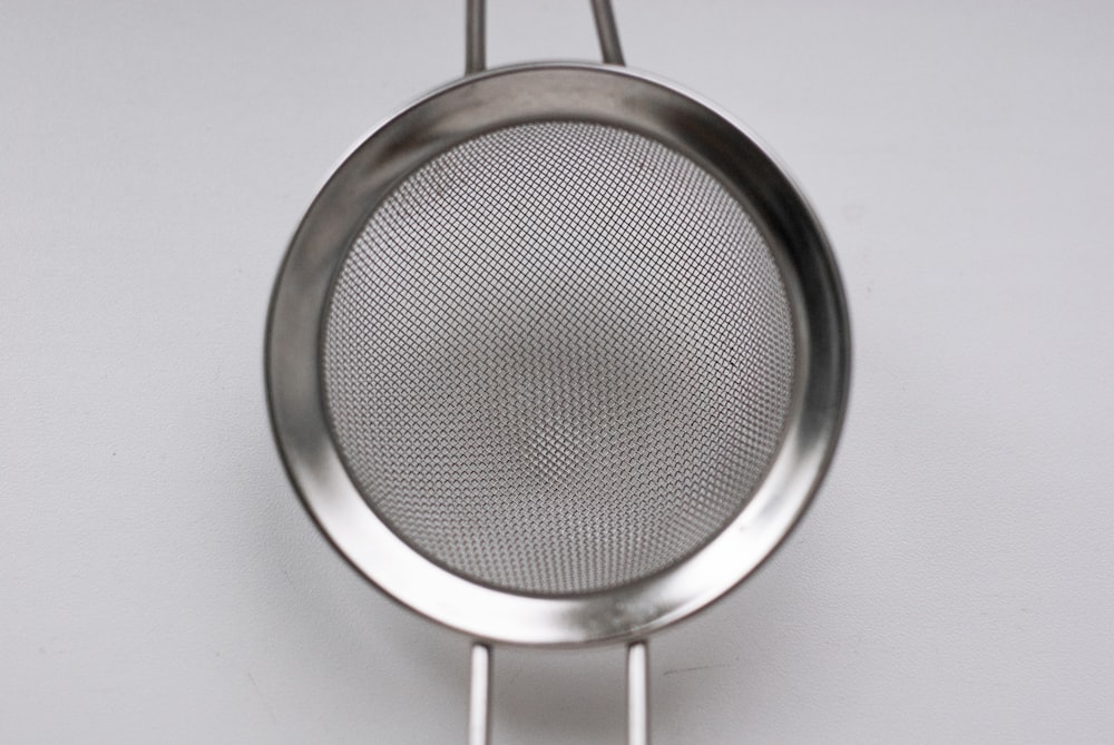 a stainless steel strainer hanging on a wall