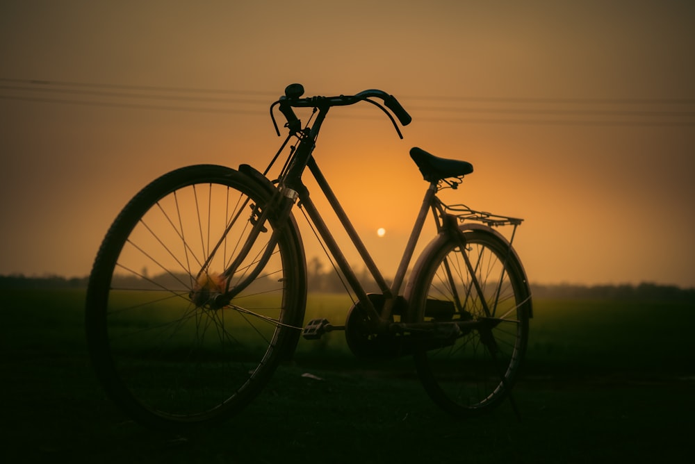 a bike parked in a field at sunset