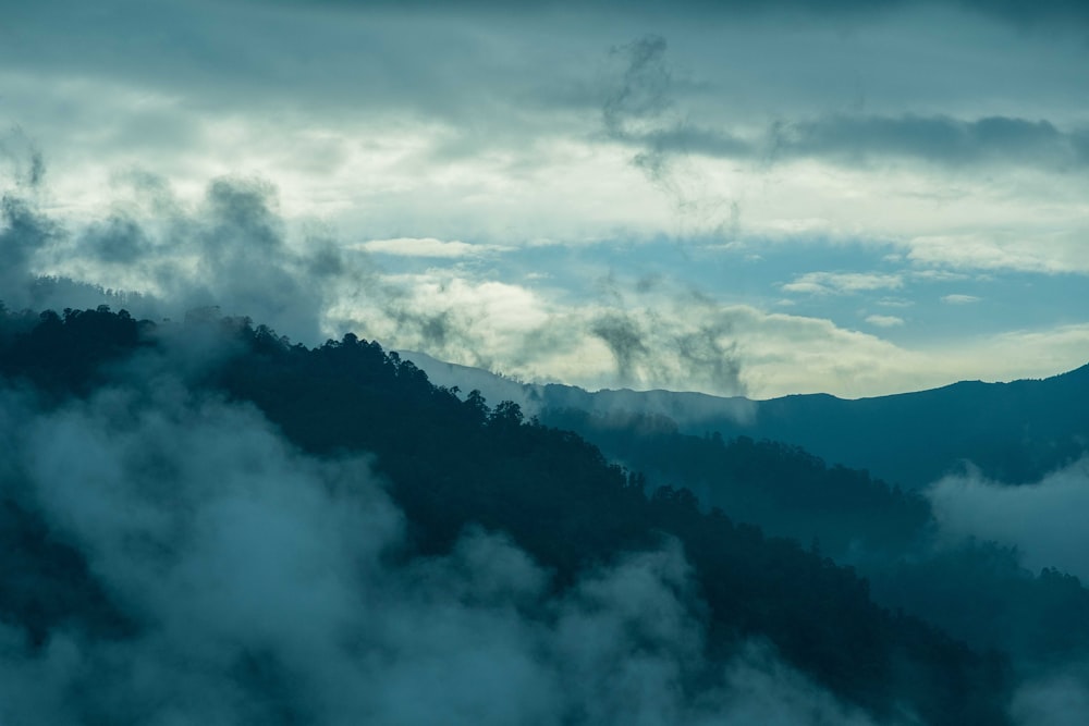 a mountain covered in fog and clouds under a cloudy sky