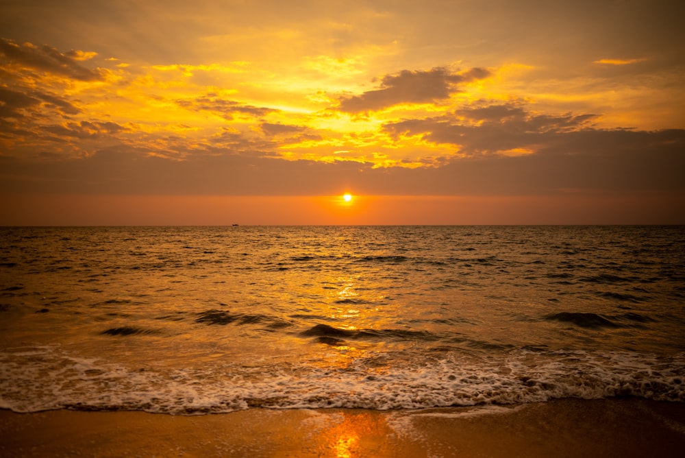 the sun is setting over the water at the beach