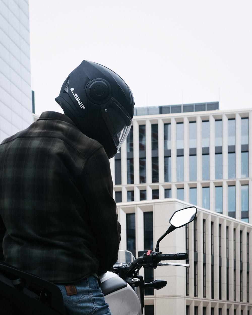 a man in a black jacket and helmet on a motorcycle