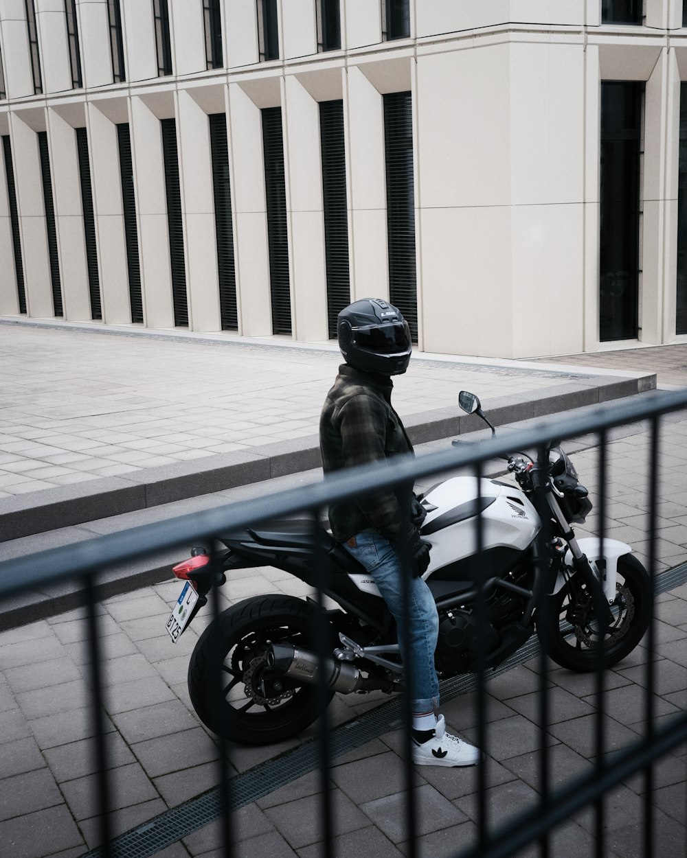 a person sitting on a motorcycle on a sidewalk