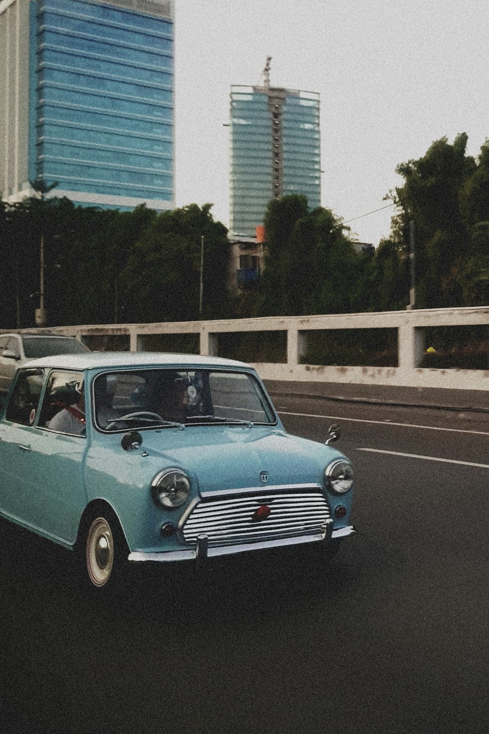 a blue car driving down a street next to tall buildings