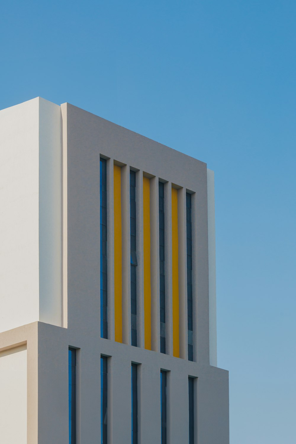 a tall white building with yellow and blue windows