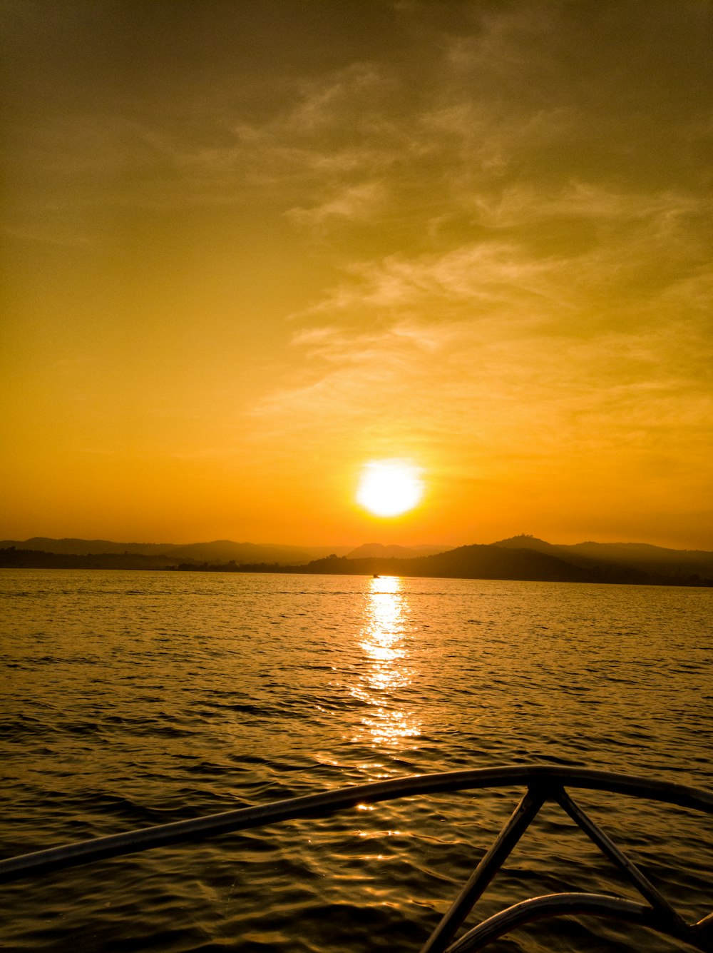 the sun is setting over the water on a boat