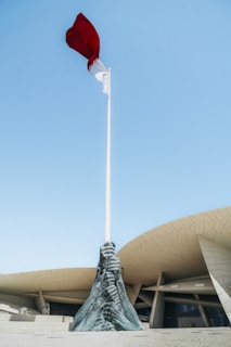 a red and white flag on top of a white pole