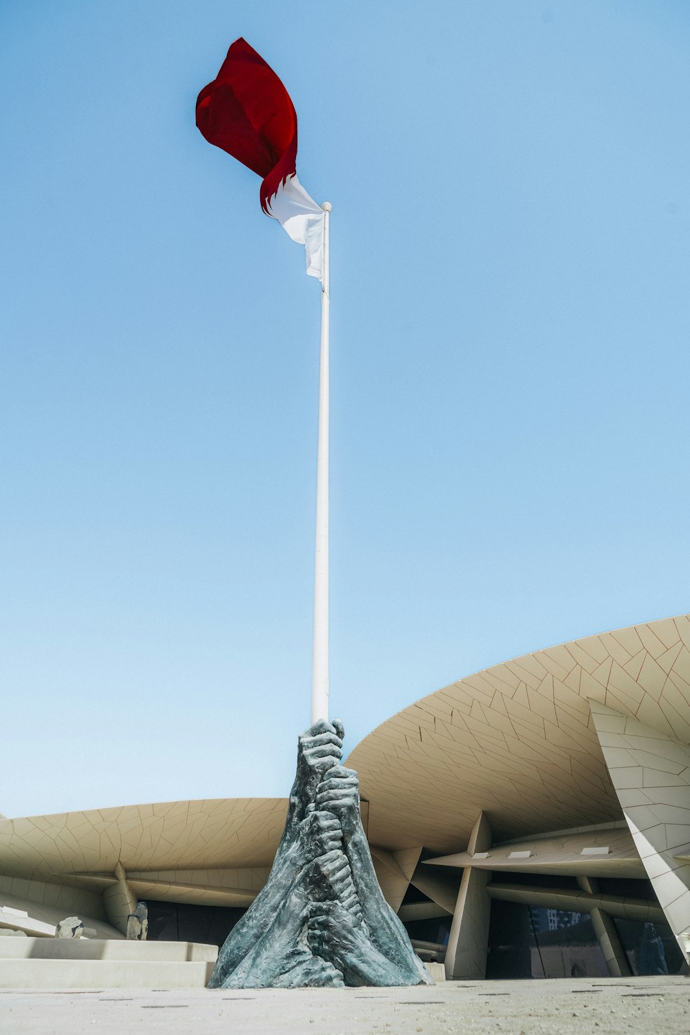 a red and white flag on top of a white pole