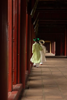two young girls are walking down a long corridor