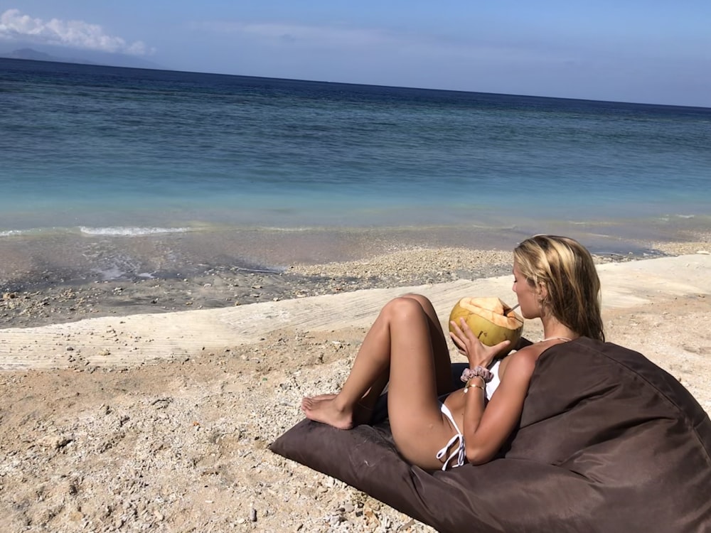 a woman sitting on a bean bag on the beach