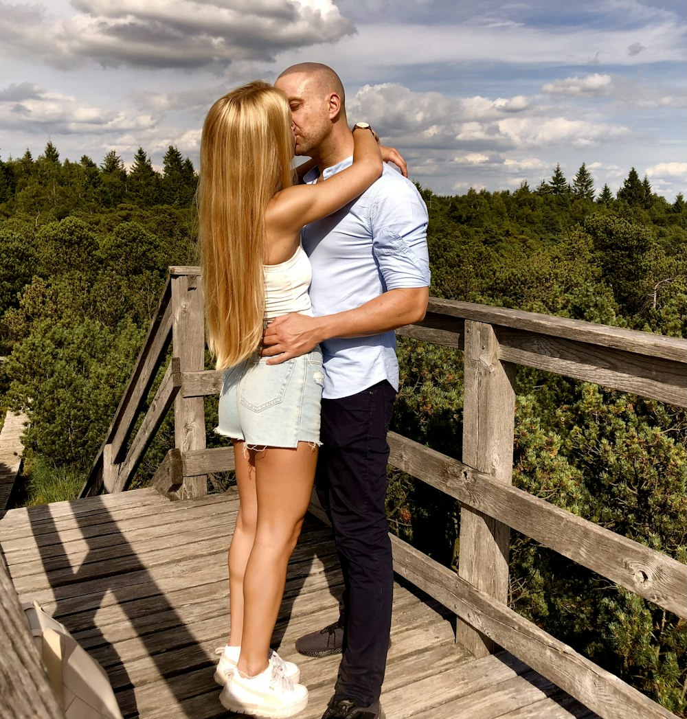 a man and a woman kissing on a bridge