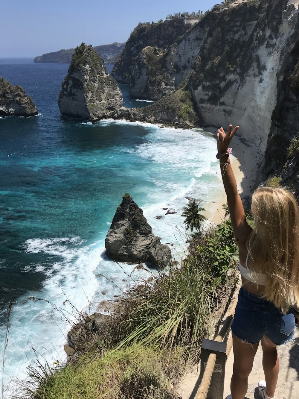 a woman standing on top of a cliff next to the ocean