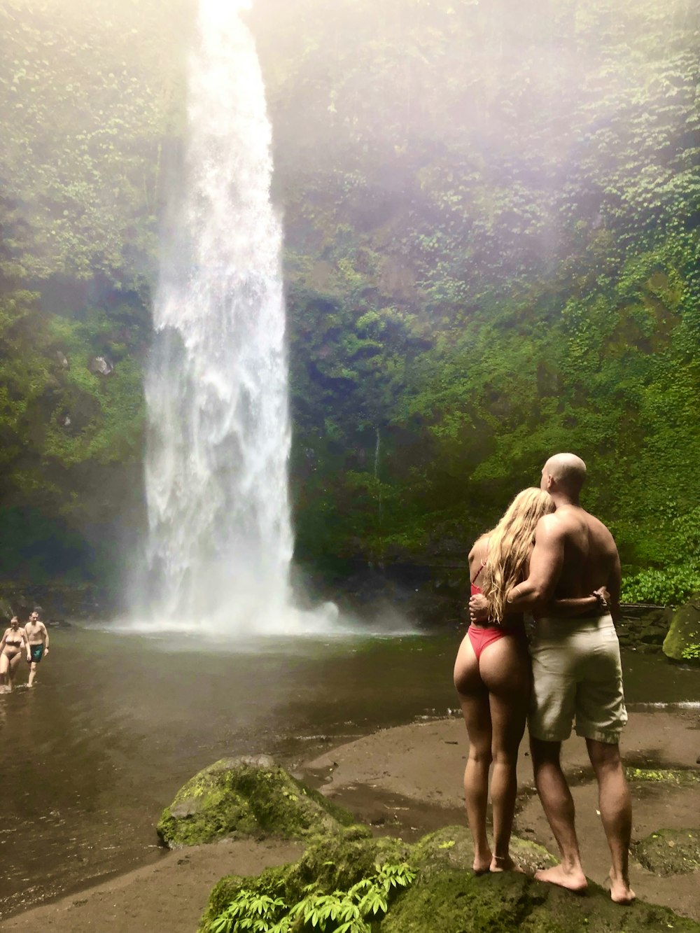 a man and a woman standing in front of a waterfall