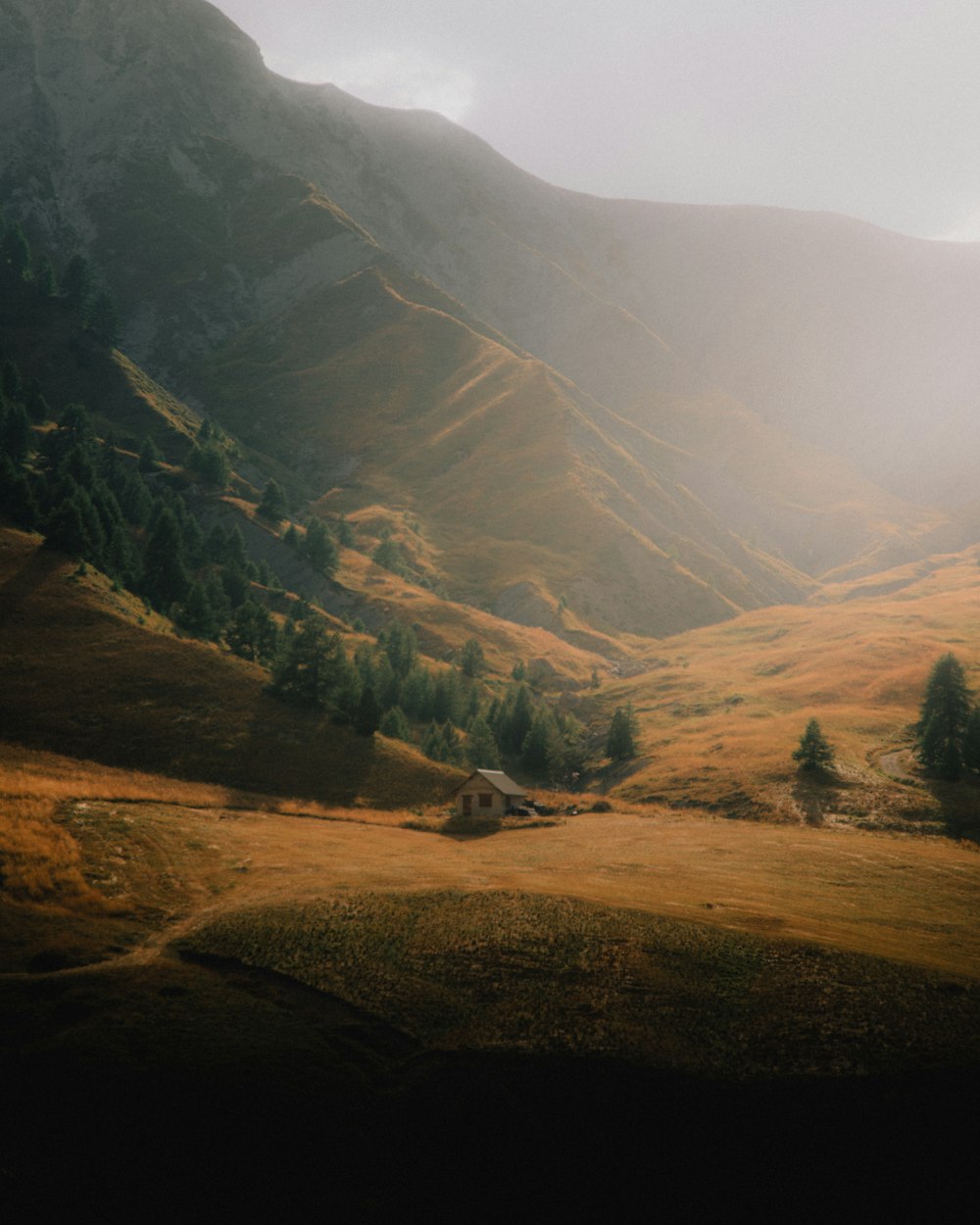 a house in the middle of a field with mountains in the background