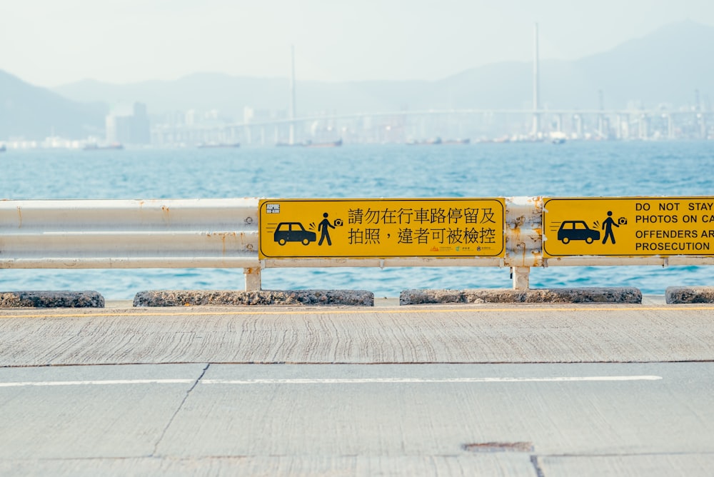 a yellow sign on the side of a road next to the ocean