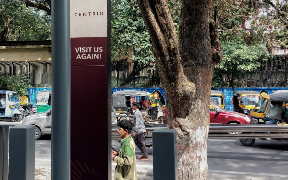 a group of people walking down a street next to a tree