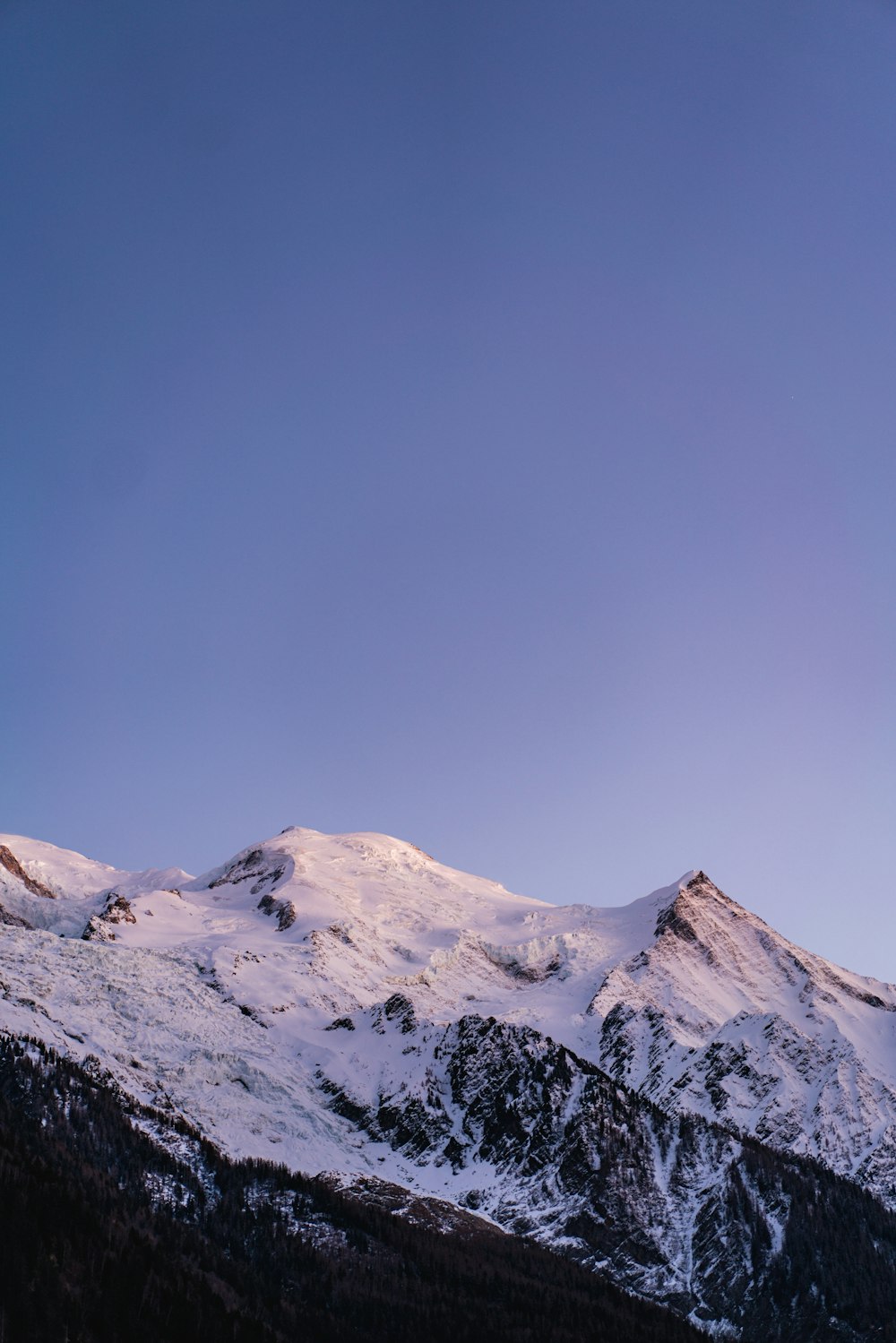 a snow covered mountain range under a blue sky