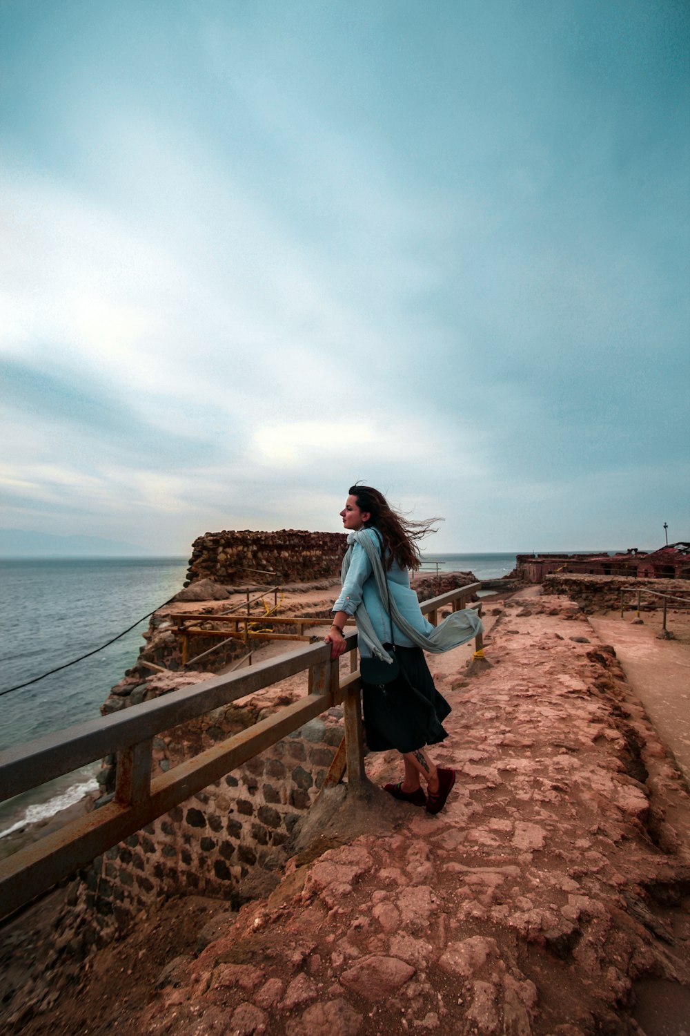 a woman standing on a bridge next to the ocean