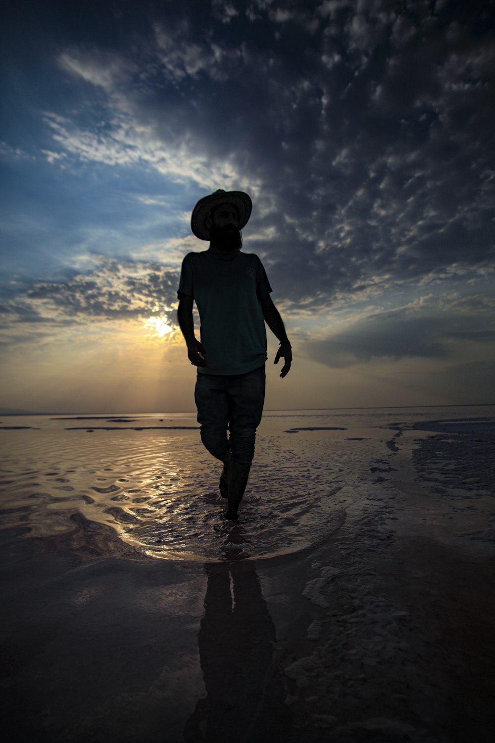 a man walking on the beach at sunset