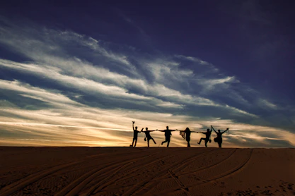 a group of people standing on top of a sandy beach