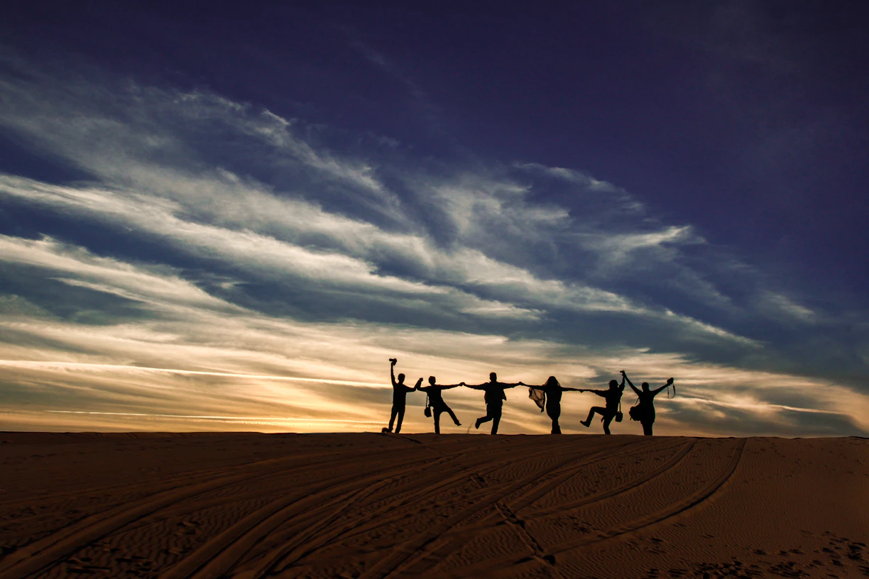 a group of people standing on top of a sandy beach