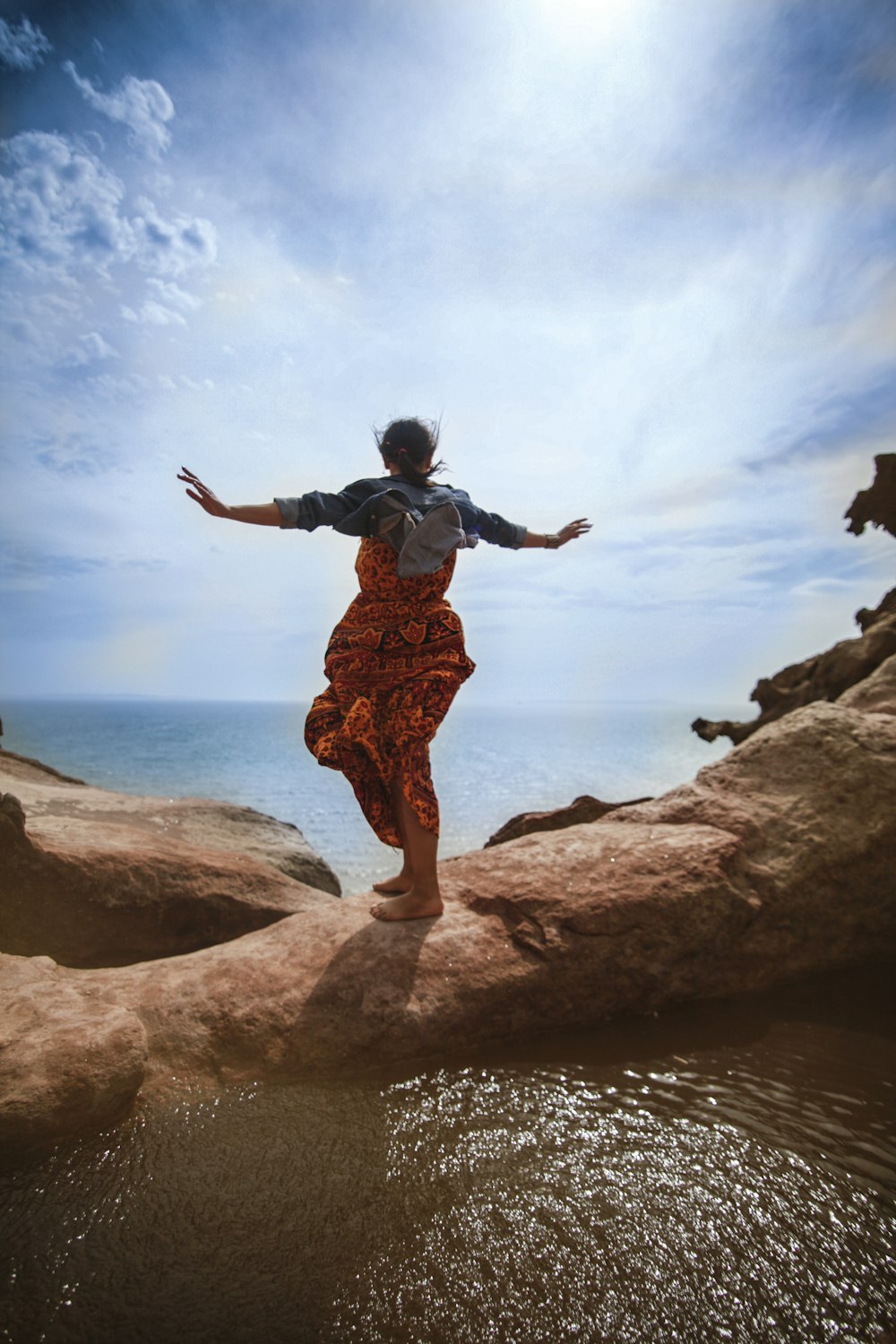 a person standing on a rock by the water