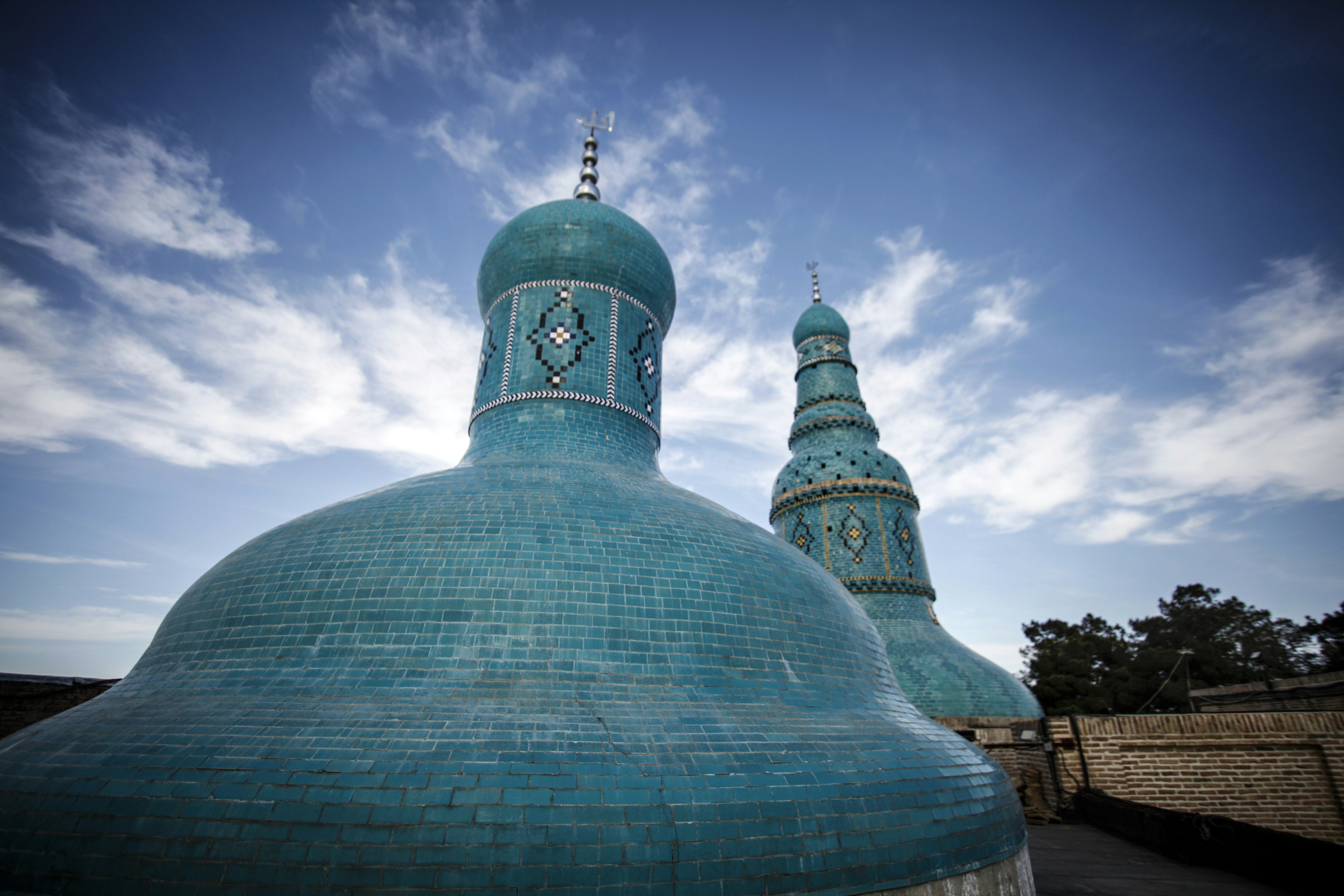 a large blue building with two towers and a sky background
