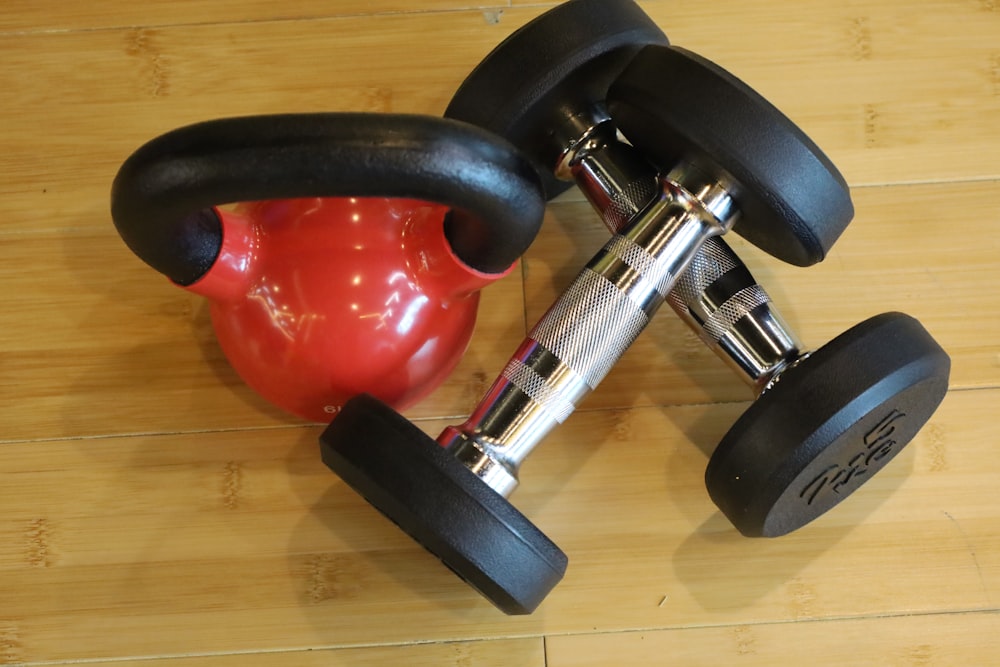 a pair of dumbbells and a red ball on a wooden floor