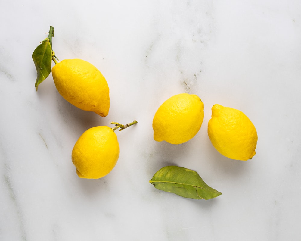 three lemons and three leaves on a marble surface