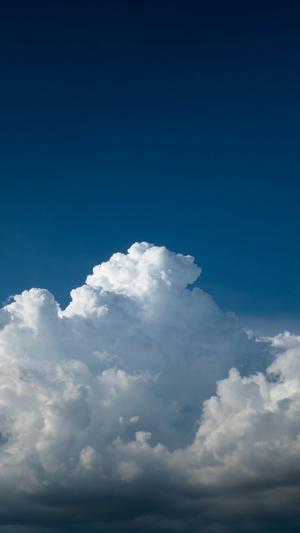 a plane flying through a cloudy blue sky