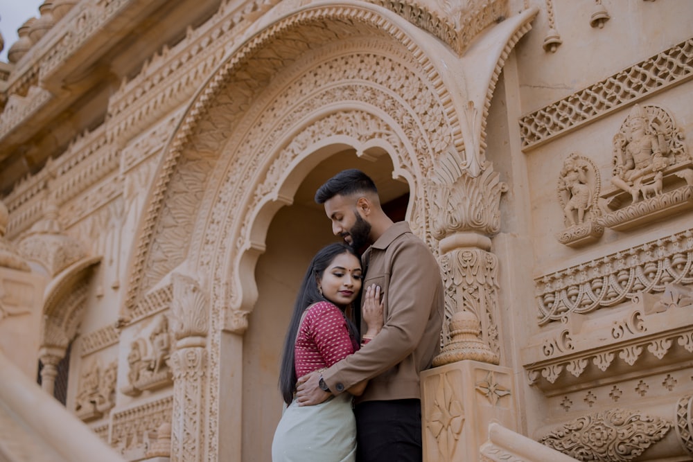 a man and a woman standing next to each other in front of a building