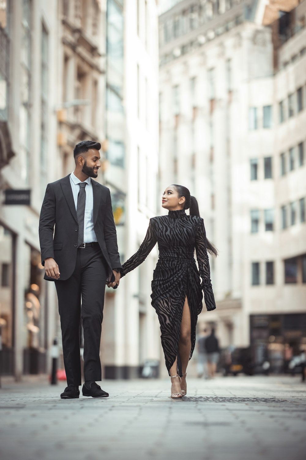 a man and a woman walking down a street holding hands