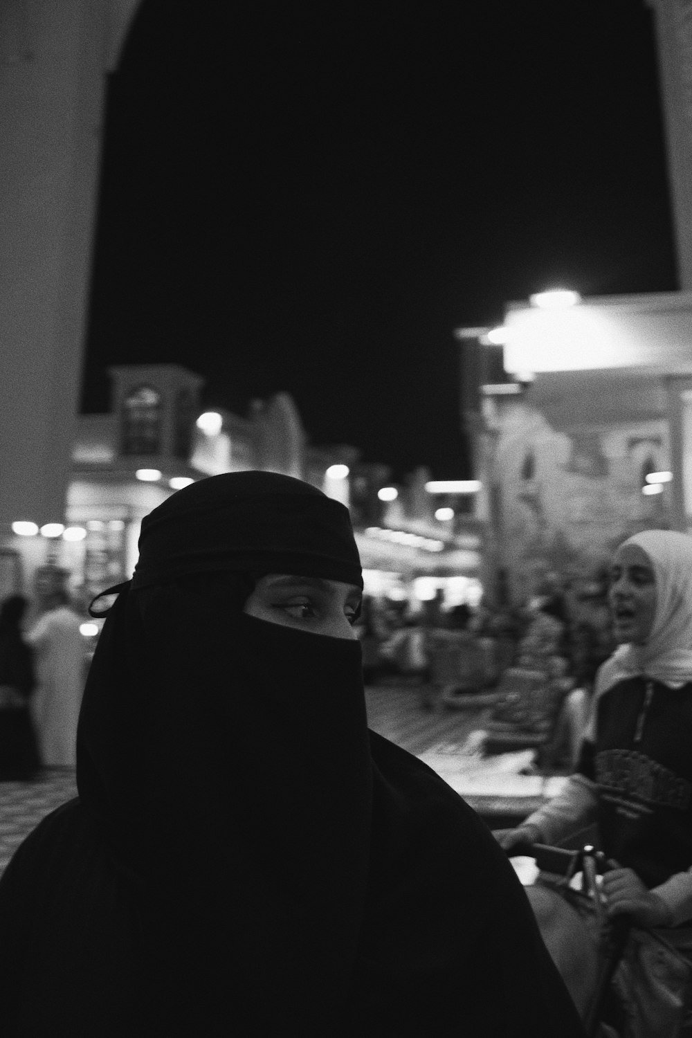 a woman in a hijab standing in front of a crowd of people