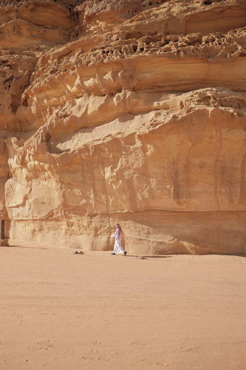 une femme en robe blanche debout devant une formation rocheuse