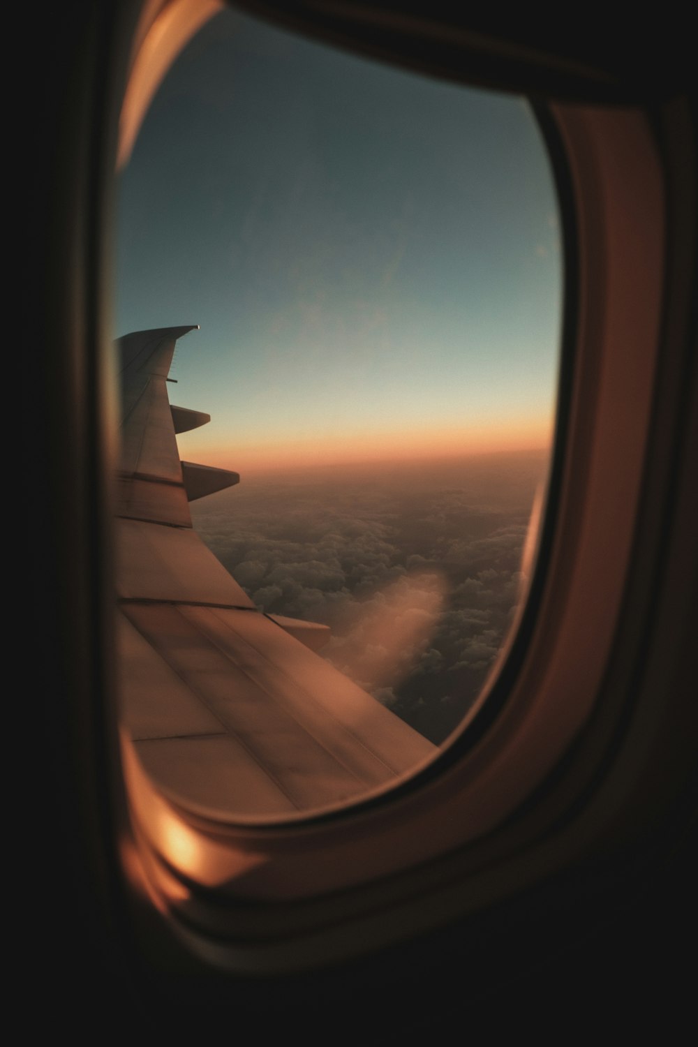 a view of the wing of an airplane as it flies over the clouds