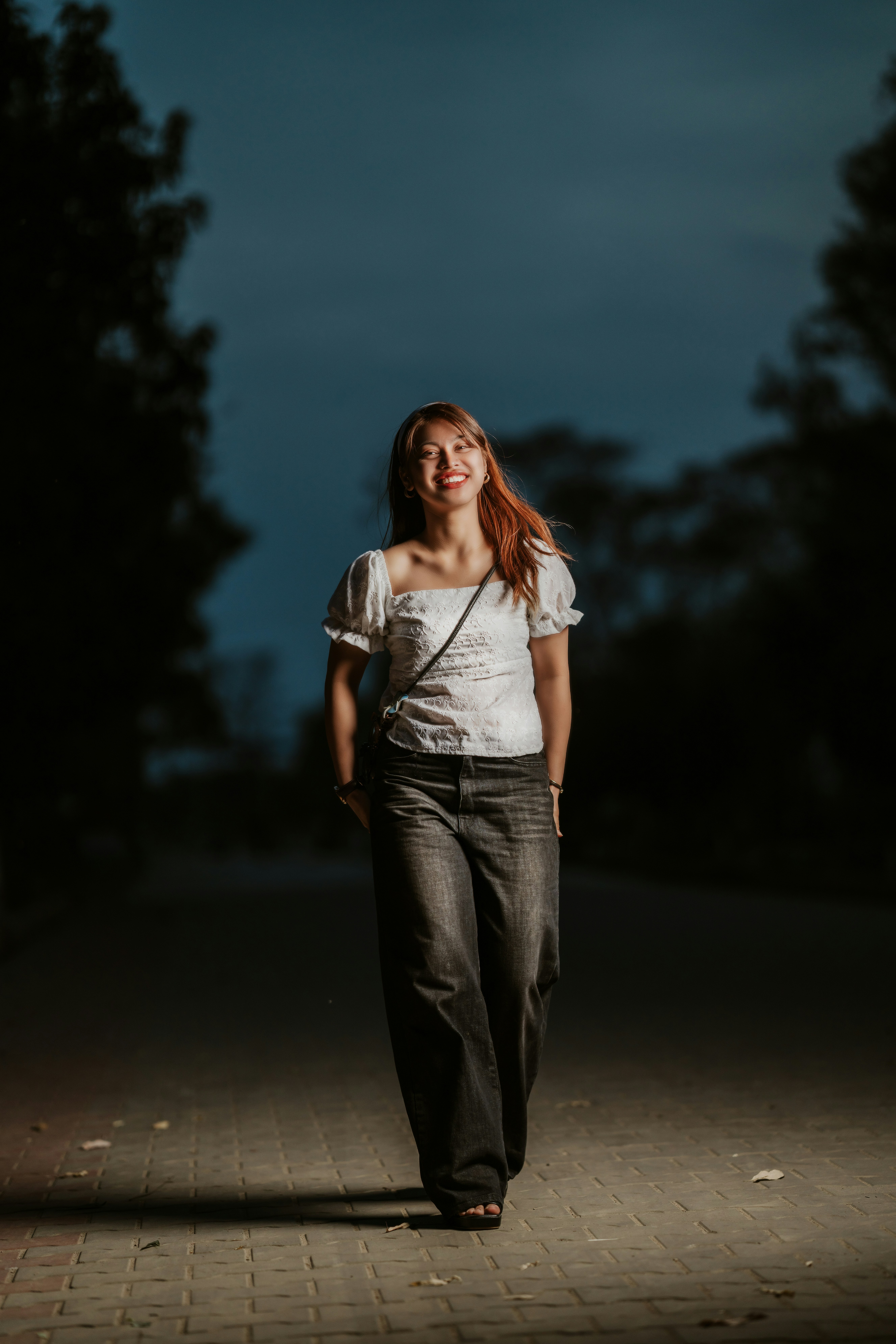 a woman walking down a sidewalk at night