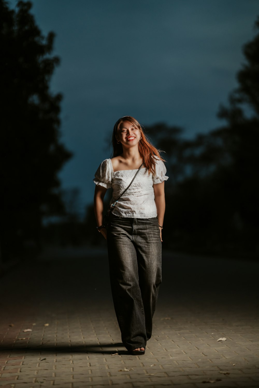 a woman walking down a sidewalk at night