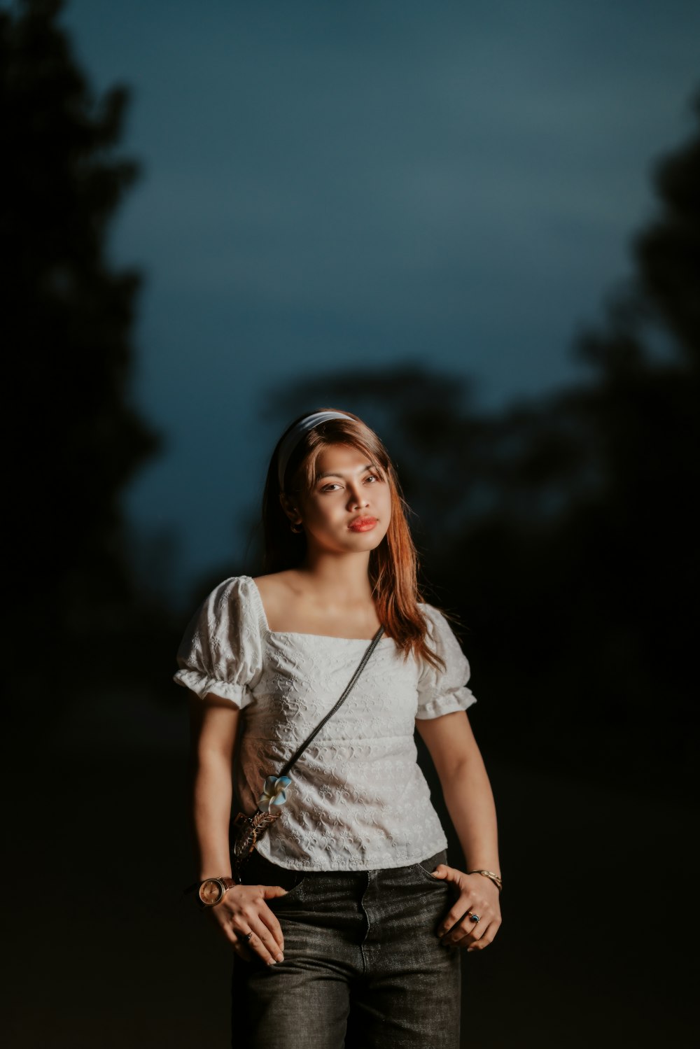 a woman standing in the dark with her hands on her hips