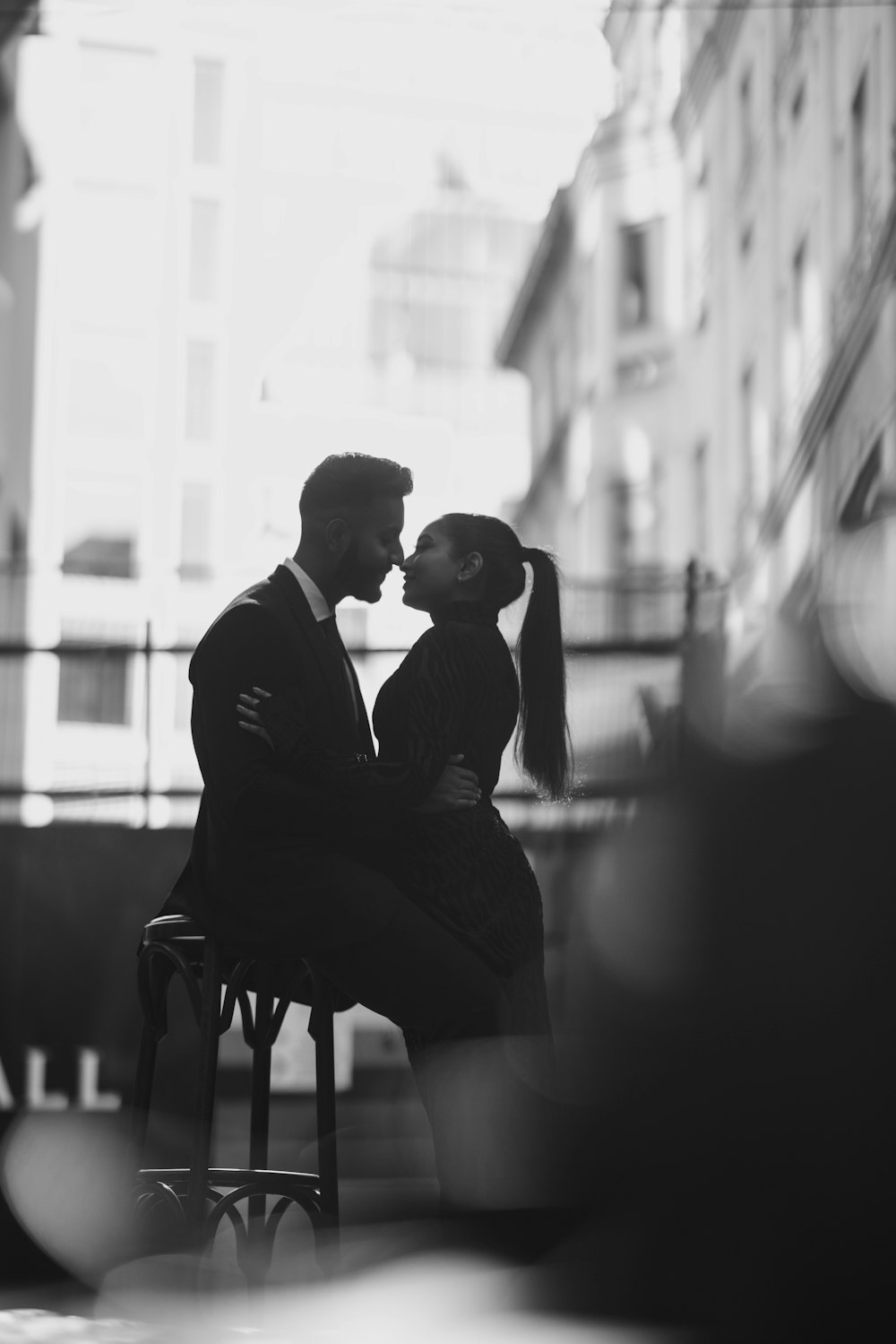 a black and white photo of a couple kissing