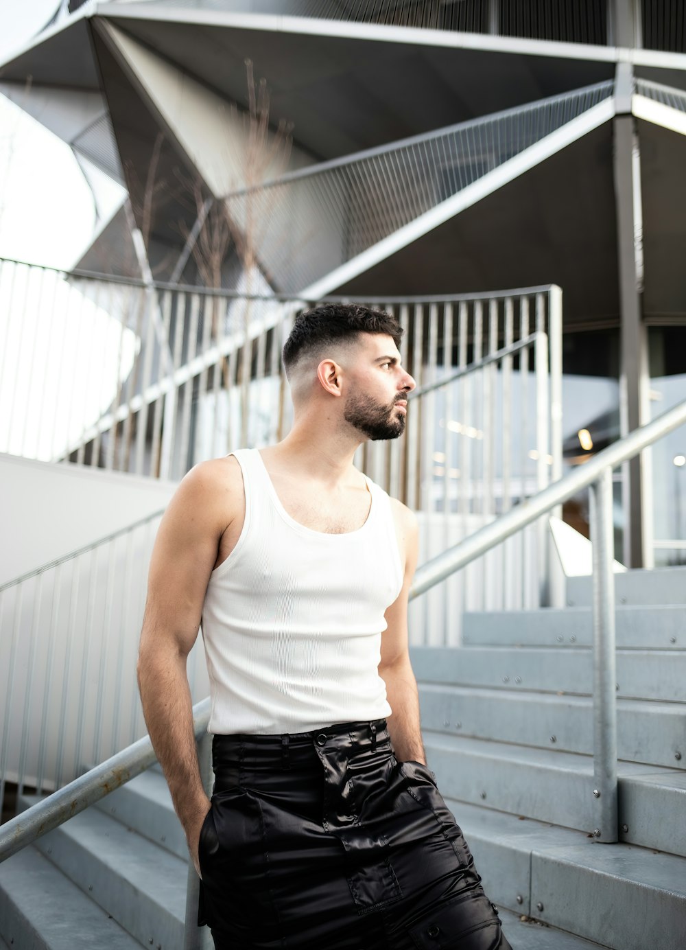 a man standing on a set of stairs wearing a white tank top