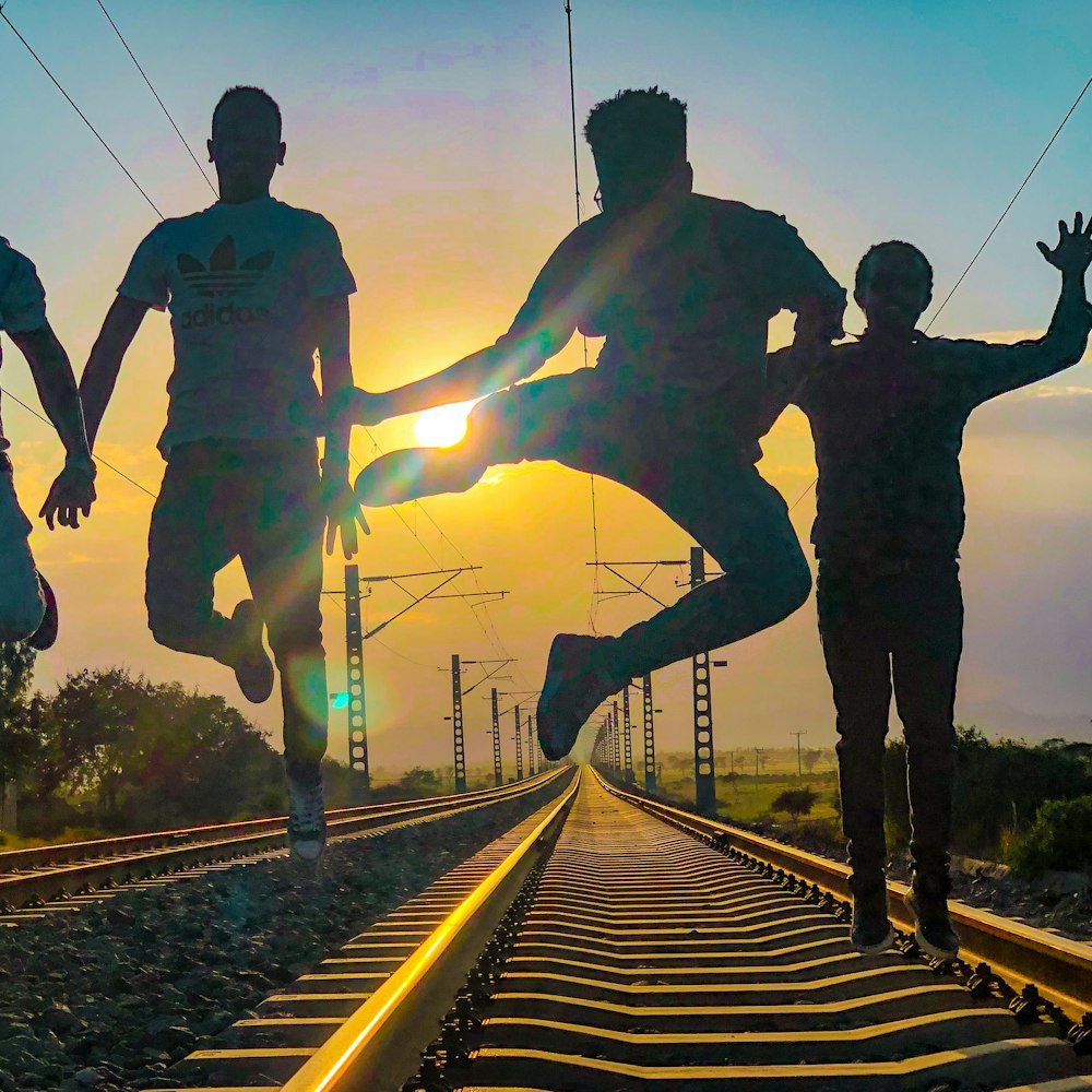 a group of people running across a train track