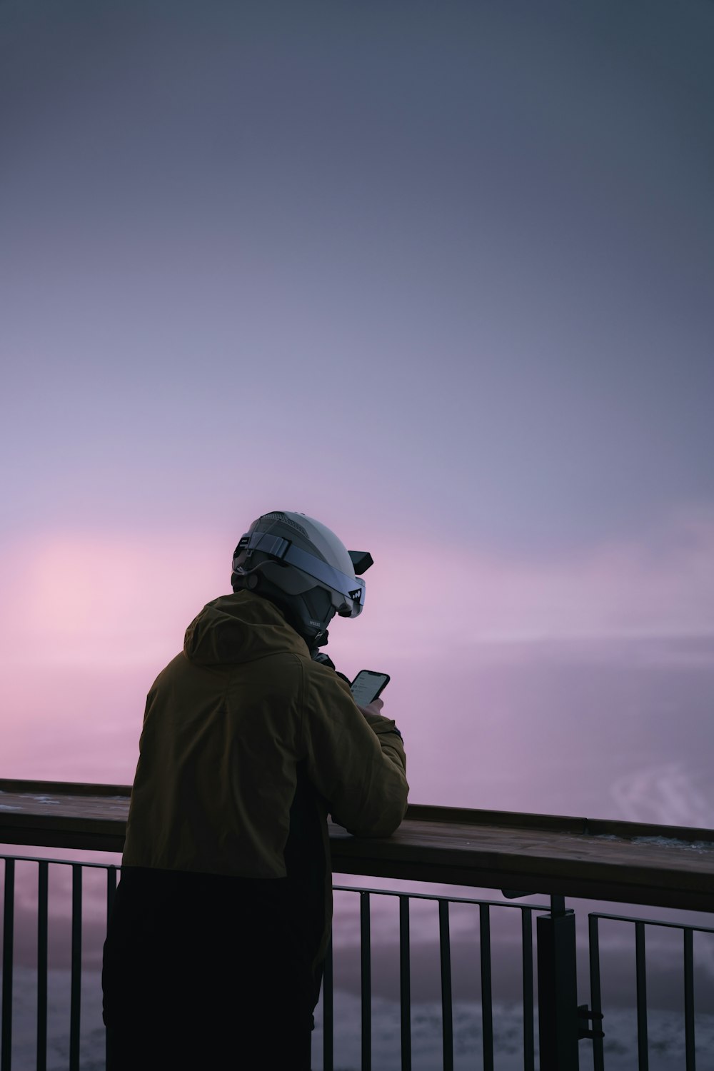 a man standing next to a railing looking at his cell phone