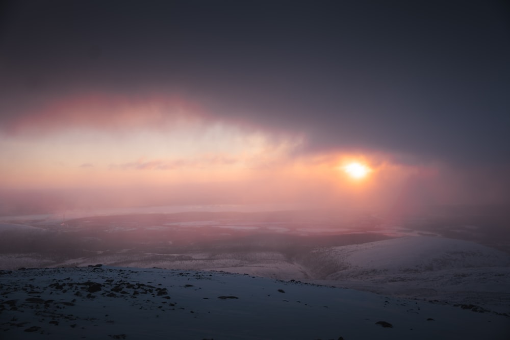 the sun is setting over a snowy landscape