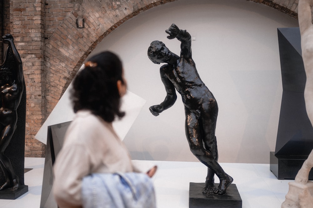 a woman looking at a statue in a museum