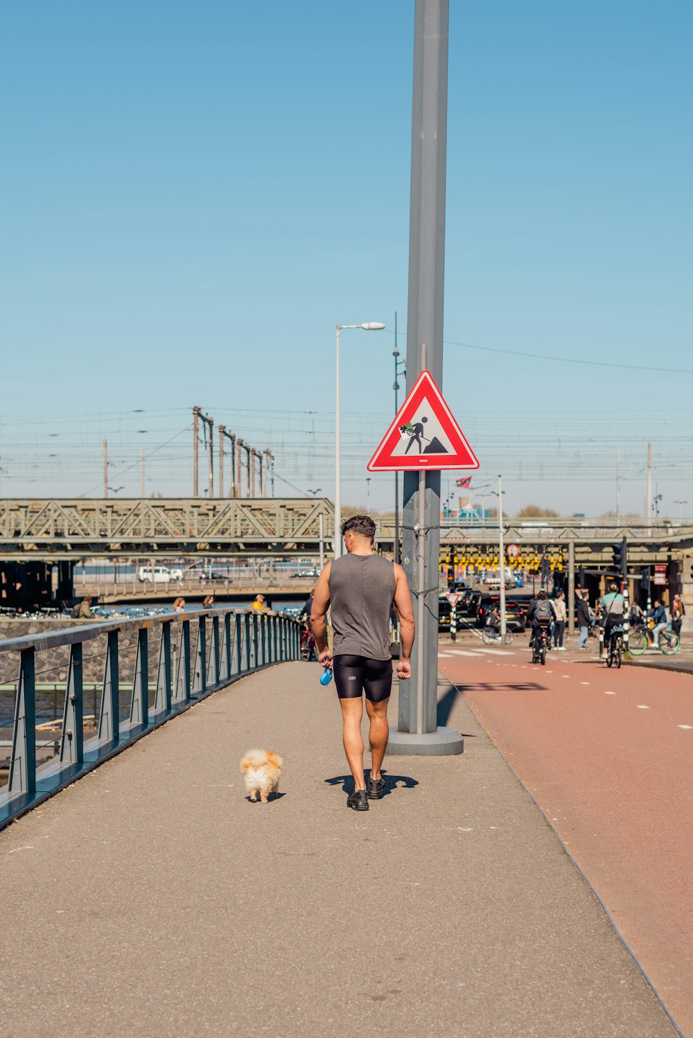 a man walking down a sidewalk next to a dog