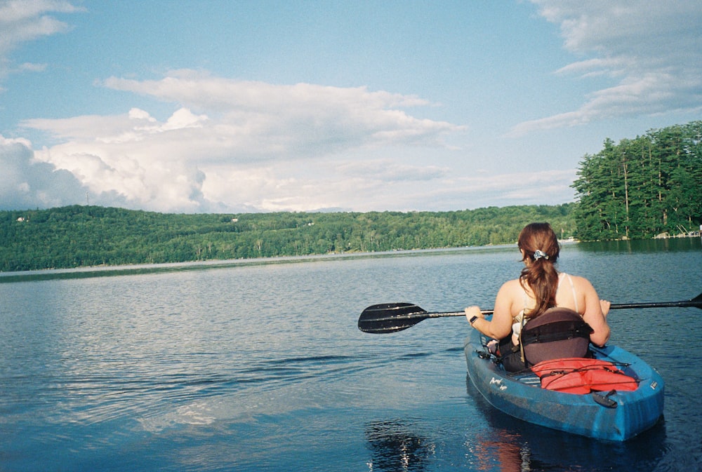 a woman paddling a canoe on a lake